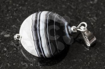 pendant from striped polished Agate gemstone on black granite background