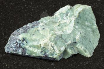 natural mineral from geological collection - raw Teisky Jade (Hantigyrite, khakassian serpentine) rock with Magnetite, Serpentine, Hematite minerals from Teyskoye mine, Khakassia on black granite