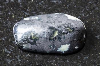 natural mineral from geological collection - tumbled Teisky Jade (Hantigyrite, khakassian serpentine) rock with Magnetite, Serpentine, Hematite minerals from Teyskoye mine, Khakassia on black granite