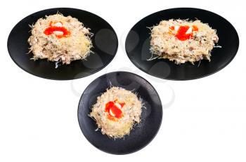 set from served Quail Nest salad from ham, veal and beef tongue, grated cheese, dressed with mayonnaise and decorated by quail egg and salmon caviar on black plate isolated on white background
