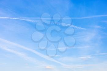 several old contrails and cirrus clouds in blue sky on autumn day