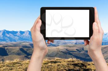 travel concept - tourist photographs of North Caucasus mountain range from Bermamyt Plateau in Russia in september on smartphone with cut out screen with blank place for advertising