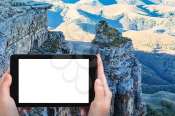 travel concept - tourist photographs of old rocks of Bermamyt Plateau at autumn morning in North Caucasus mountains of Russia on smartphone with cut out screen with blank place for advertising