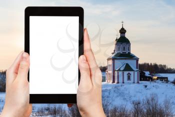 travel concept - tourist photographs of Church of Elijah the Prophet on Ivanovo Hill (Elijah Church) in Suzdal in winter of Russia on smartphone with cutout screen with blank place for advertising