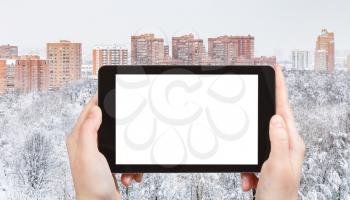 travel concept - tourist photographs of cityscape with city park and residential houses in winter in Moscow city on smartphone with empty cutout screen with blank place for advertising