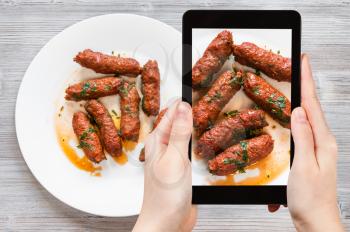 travel concept - visitor photographs of Indian cuisine of Mutton Seekh Kabab (Hyderabadi Seekh) from minced lamb meat roasted on skewers in tandoor on smartphone