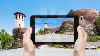 travel concept - tourist photographs of entrance to Old Ankara Castle on Gozcu square of Ankara city on smartphone in Turkey in spring