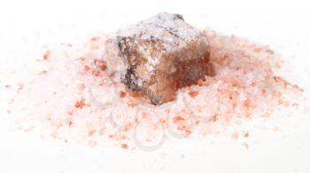 rough Halite mineral in pile of grained pink Himalayan Salt on white background