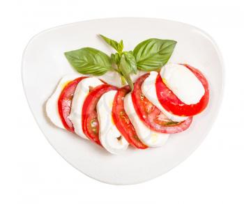 italian cuisine insalata caprese (caprese salad) - top view of sliced mozzarella cheese and tomato with basil twig seasoned by olive oil on plate isolated on white background