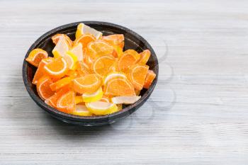 sweet sugar lemon and orange marmalade slices in ceramic bowl on gray wooden table