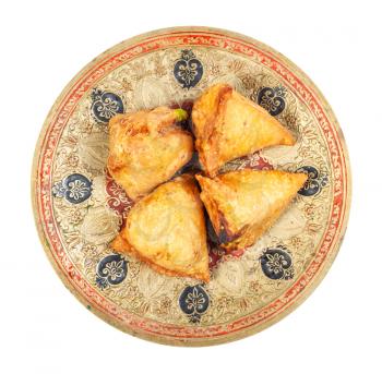 Indian cuisine - top view of keema samosas (fried savoury pastry filled by meat and vegetables) on brass plate isolated on white background