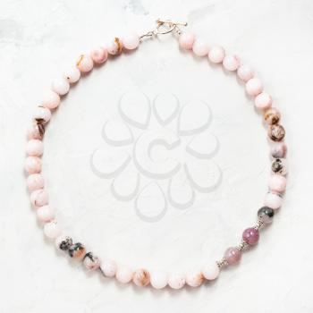 hand crafted necklace from cherry blossom rose quartz beads on gray concrete background