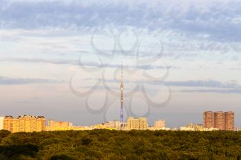 residential district with TV tower illuminated by sun and lush green forest at September sunset in Moscow city