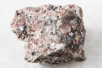 closeup of sample of natural mineral from geological collection - rough pink Granite rock on white marble background