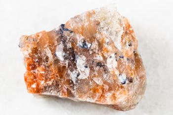 closeup of sample of natural mineral from geological collection - rough red Rock Salt (Halite) on white marble background from Perm Krai, Russia