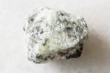 closeup of sample of natural mineral from geological collection - rough saccharoidal Apatite rock on white marble background from Khibiny, Kola Peninsula, Russia