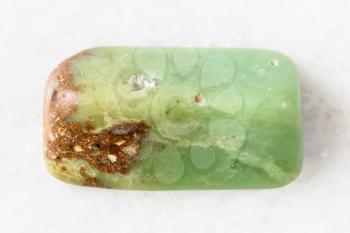 closeup of sample of natural mineral from geological collection - polished Chrysoprase rock on white marble background from Newman, Australia