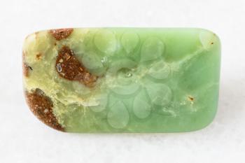 closeup of sample of natural mineral from geological collection - tumbled Chrysoprase rock on white marble background from Newman, Australia