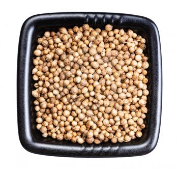 top view of dried coriander seeds in black bowl isolated on white background