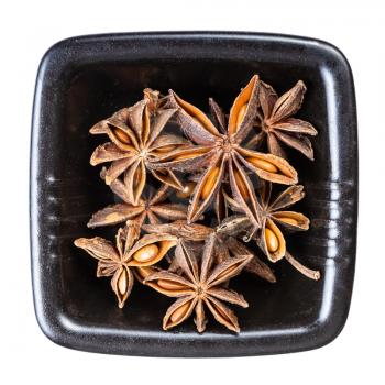 top view of dried star anise (badian) fruits in black bowl isolated on white background