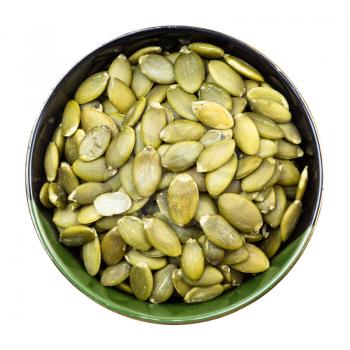 top view of hulled pumpkin seeds in round bowl isolated on white background