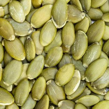 square food background - hulled pumpkin seeds close up