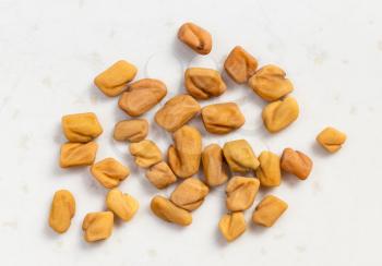 several whole fenugreek seeds close up on gray ceramic plate