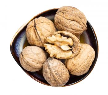 top view of shelled and few whole walnuts in ceramic bowl isolated on white background