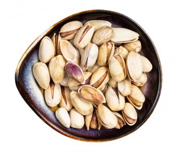 top view of shelled and ripe pistachio nuts in ceramic bowl isolated on white background