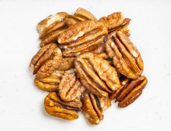 top view of pile of shelled pecan nuts close up on gray ceramic plate