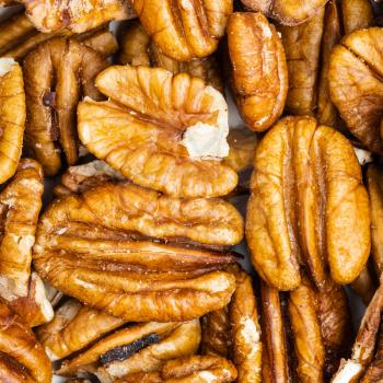 square food background - shelled pecan nuts close up