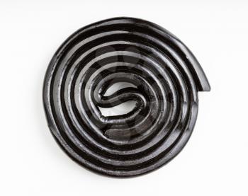 top view of spiral from black liquorice candy on white plate