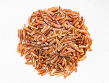top view of pile of raw red rice close up on gray ceramic plate