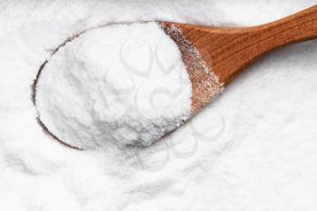 top view of wood spoon with dextrose sugar close up on pile of sugar