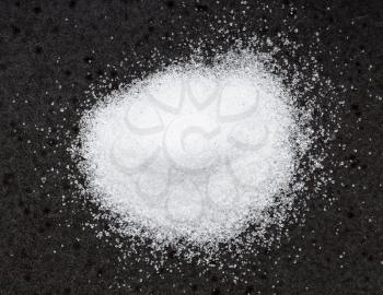 top view of pile of crystalline erythritol sugar substitute close up on black ceramic plate