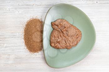 top view of teff grains and boiled porridge on green plate on wooden table