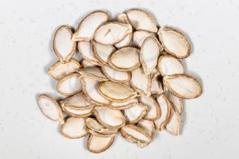 top view of pile of whole pumpkin seeds close up on gray ceramic plate