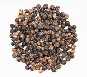 top view of pile of black pepper peppercorns close up on gray ceramic plate