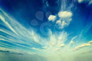 Retro image of blue sky with clouds in vintage hipster style with overlaid textire