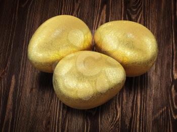 Three golden Easter eggs isolated on wooden background