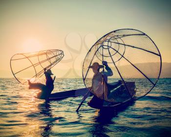 Myanmar travel toursist attraction landmark - two traditional Burmese fishermen at Inle lake, Myanmar on sunrise. Vintage filtered retro effect hipster style image