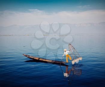 Myanmar travel attraction - Traditional Burmese fisherman with fishing net at Inle lake, Myanmar famous for their distinctive one legged rowing style. Vintage filtered retro effect hipster style image