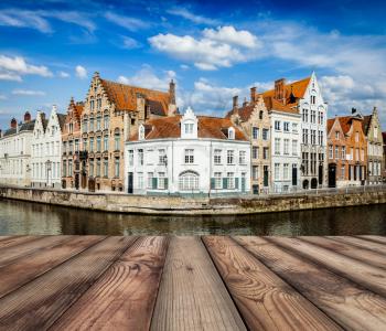 Wooden planks with European view of  Bruges canal and old historic houses of medieval architecture in background. Brugge, Belgium