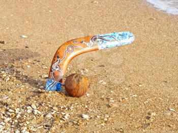 Colorful boomerang and coconut on a sandy beach.