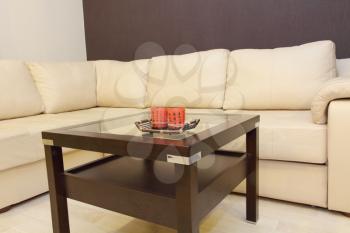 Coffee table and comfortable white corner leather sofa in room.