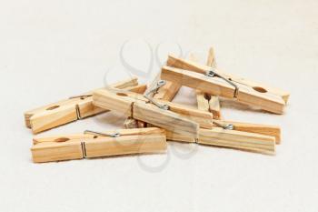 Heap of wooden clothespins taken closeup on white fabric background.