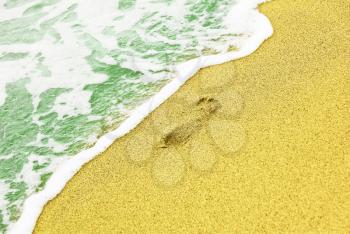 Human trace on sandy beach near azure sea surf taken closeup.