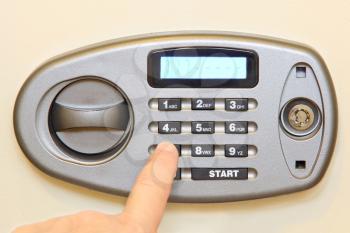 Man finger press button on electronic home safe taken closeup.