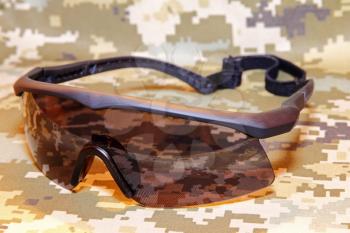 Military tactical goggles on camouflage background.