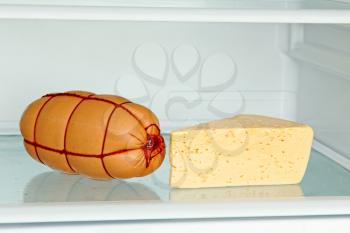 Fresh appetizing sausage and cheese on refrigerator shelf taken closeup.